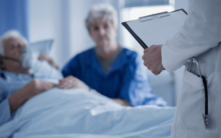 Doctor with stethoscope in the pocket of a white apron holding results of elderly patient