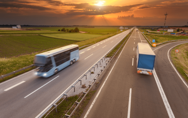 Truck and bus driving in motion blur on the freeway towards the setting sun