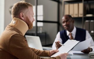 A man filling out documents at an insurance agency, representing the importance of proper documentation and evidence in personal injury cases.