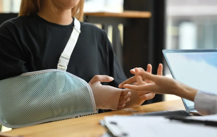 Injured patient with arm in sling during consultation about insurance settlement.