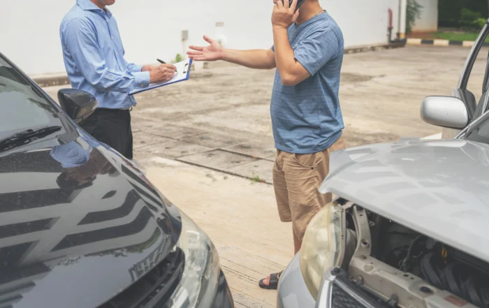Two men discussing a Louisiana car accident while exchanging information with damaged vehicles nearby